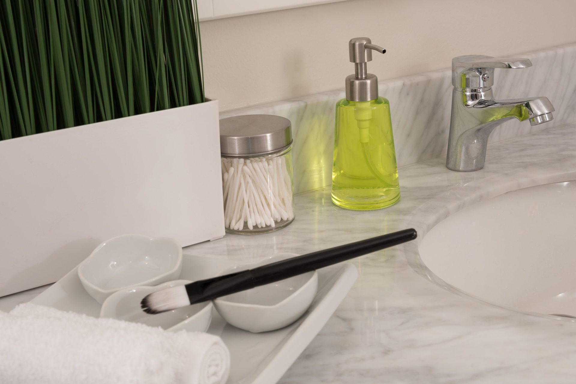 Primer plano de un tocador de baño con una decoración elegante, que incluye dispensador de jabón y plantas decorativas.